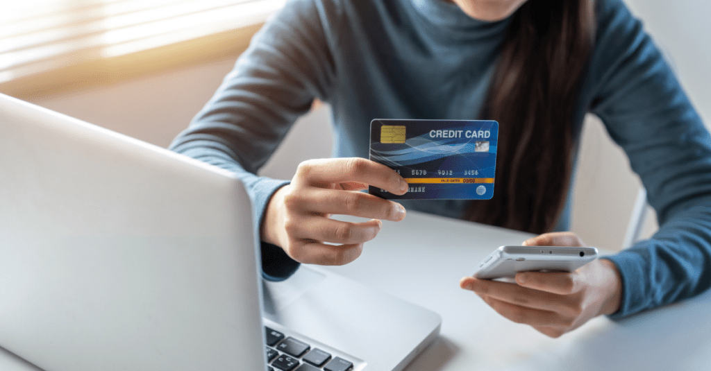 A woman filing chargebacks is holding a credit card in front of a laptop computer